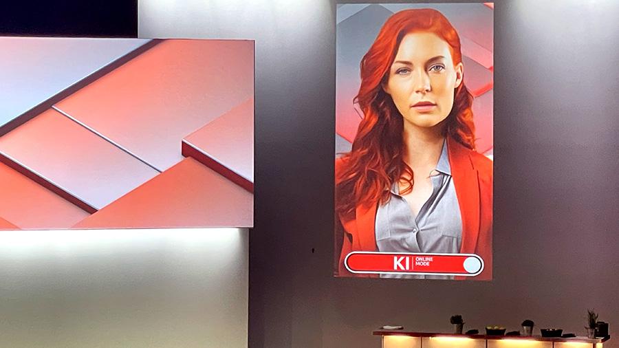 KI-Moderatorin KIRA mit animierten Outfits und synthetischer Stimme moderiert durch das Event.